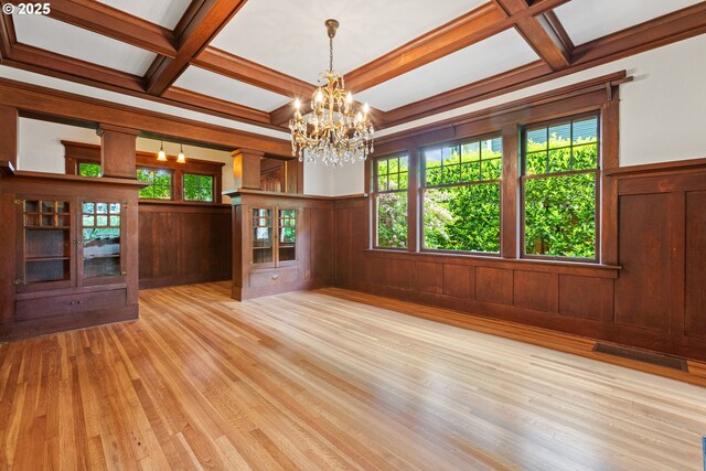 unfurnished dining area featuring wood finished floors, coffered ceiling, visible vents, beamed ceiling, and a chandelier