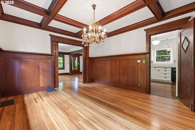 unfurnished dining area with coffered ceiling, light wood-type flooring, and visible vents