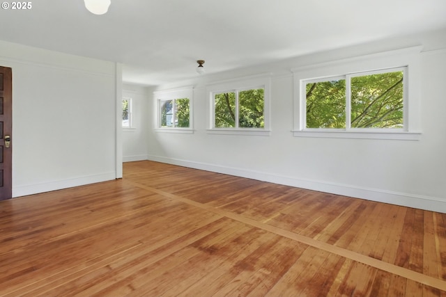 spare room featuring wood-type flooring and baseboards