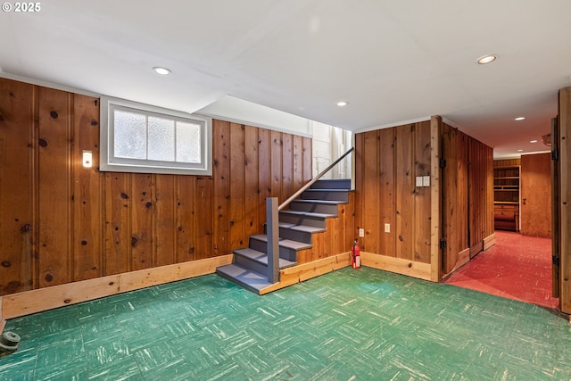 below grade area featuring wood walls, stairs, carpet, recessed lighting, and baseboards