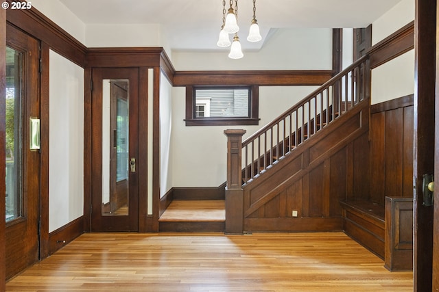 foyer entrance featuring stairway, a chandelier, light wood-style flooring, and baseboards