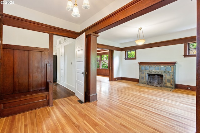 unfurnished living room featuring a fireplace with flush hearth, baseboards, light wood-type flooring, and plenty of natural light