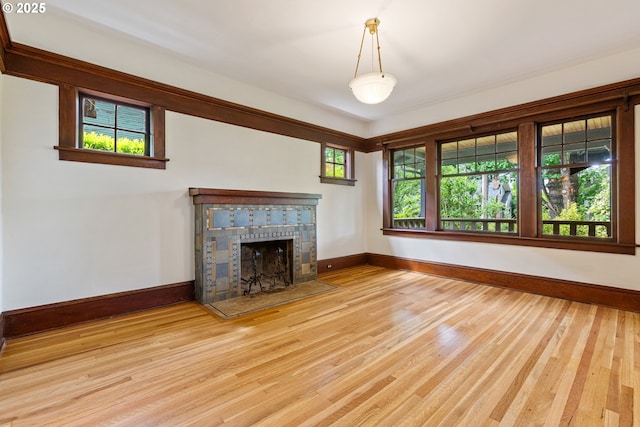 unfurnished living room with baseboards, a tile fireplace, and wood finished floors