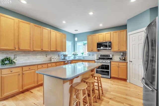 11433 SE Bethany Dr, Happy Valley, OR 97086 - kitchen featuring stainless steel appliances, light brown cabinets, a breakfast bar area, tasteful backsplash, and a center island