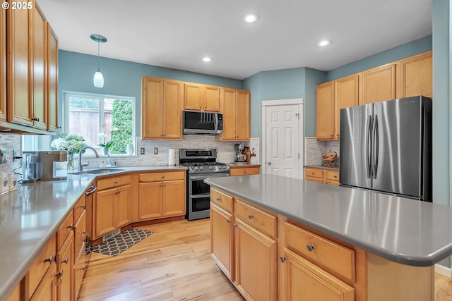 11433 SE Bethany Dr, Happy Valley, OR 97086 - kitchen featuring appliances with stainless steel finishes, decorative backsplash, light wood-style floors, light brown cabinetry, and a kitchen island