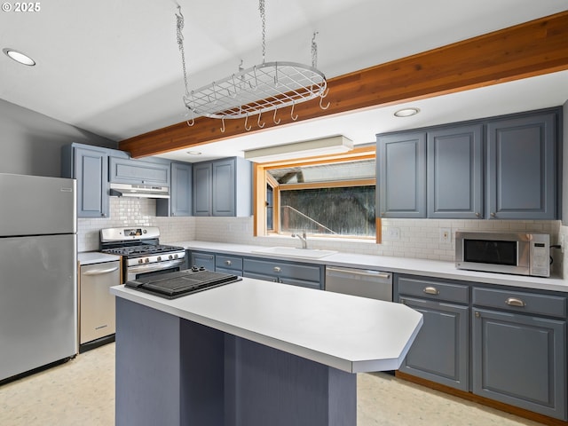6310 SW 35th Ave, Portland, OR 97221 - kitchen featuring appliances with stainless steel finishes, backsplash, under cabinet range hood, light countertops, and a kitchen island