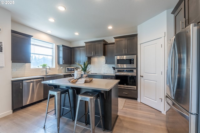 kitchen with stainless steel appliances, a breakfast bar, a kitchen island, a sink, and light countertops