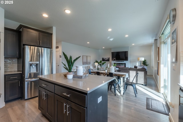 kitchen with light wood finished floors, decorative backsplash, stainless steel fridge with ice dispenser, light countertops, and recessed lighting