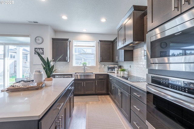 kitchen with stainless steel appliances, a sink, visible vents, light countertops, and light wood finished floors