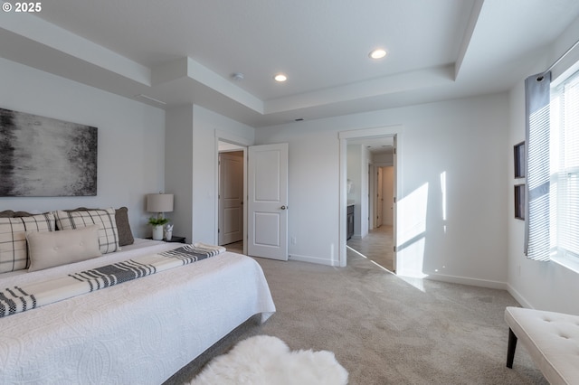 bedroom featuring a raised ceiling, light colored carpet, and baseboards