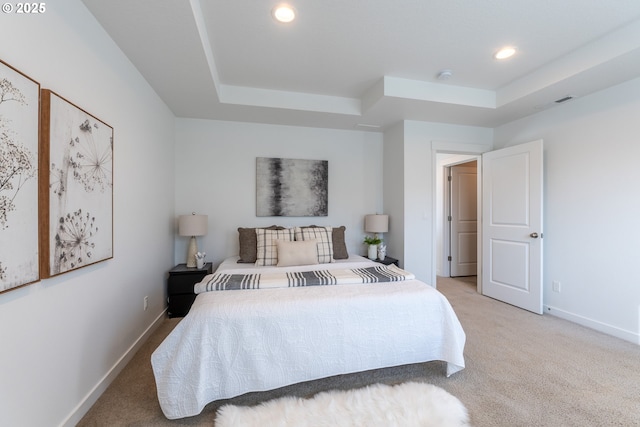 bedroom with light carpet, baseboards, and a tray ceiling