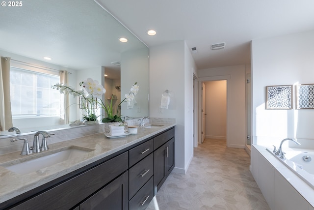 full bath with double vanity, a garden tub, visible vents, and a sink