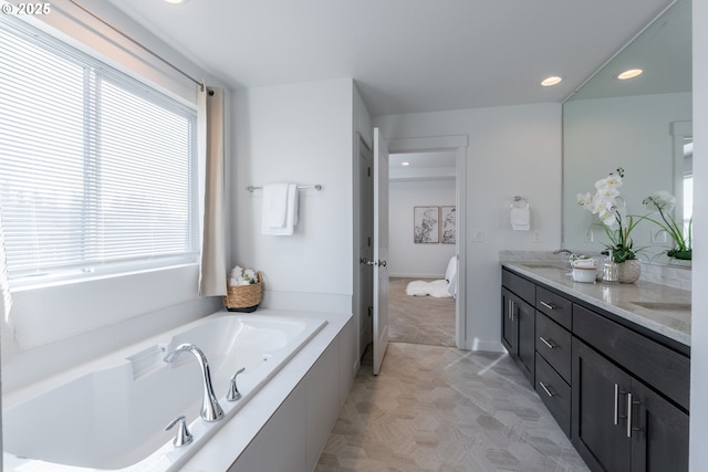 bathroom with recessed lighting, double vanity, a sink, and a bath