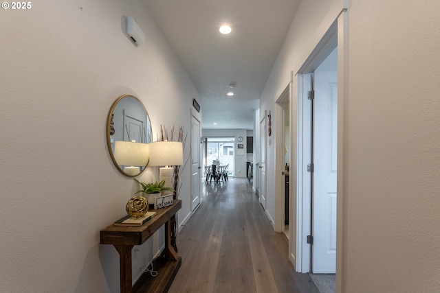 corridor with baseboards, wood finished floors, and recessed lighting