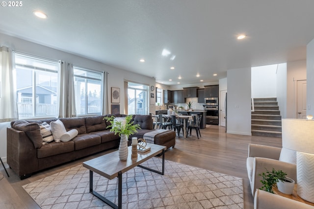 living area featuring light wood finished floors, stairway, and recessed lighting