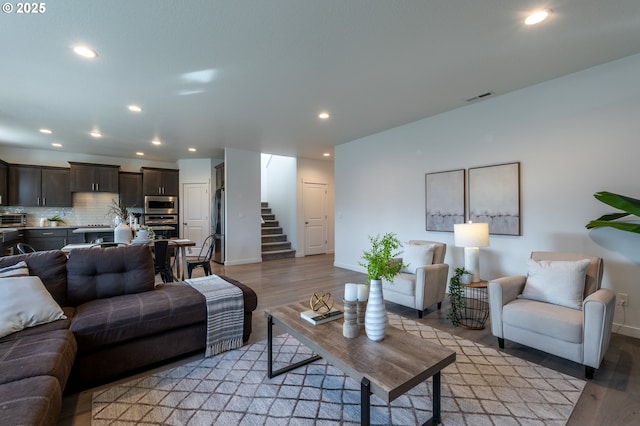 living area featuring light wood finished floors, baseboards, visible vents, stairway, and recessed lighting