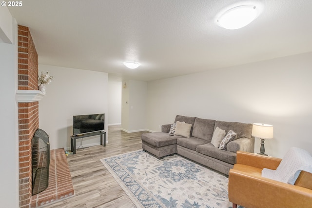 3727 NW Arrowood Cir, Corvallis, OR 97330 - living room with light wood-type flooring, a brick fireplace, baseboards, and a textured ceiling