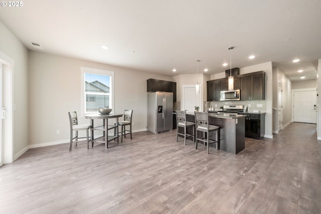 2360 N R St, Washougal, WA 98671 - kitchen featuring appliances with stainless steel finishes, a kitchen breakfast bar, an island with sink, light wood-style floors, and recessed lighting