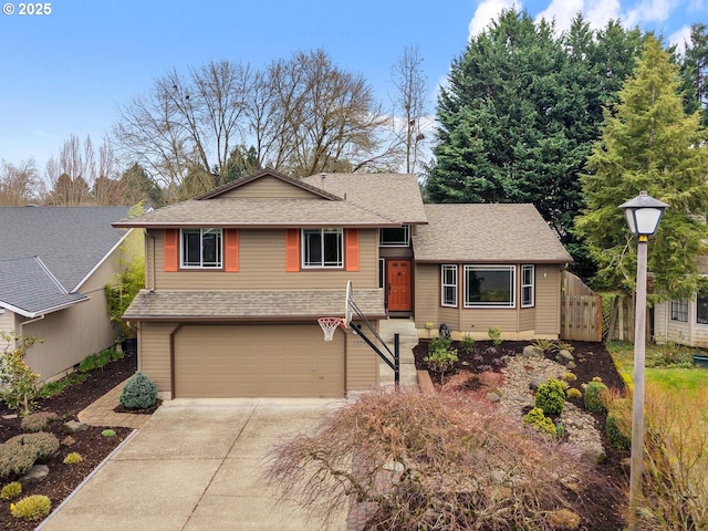 split level home featuring an attached garage, concrete driveway, roof with shingles, and fence