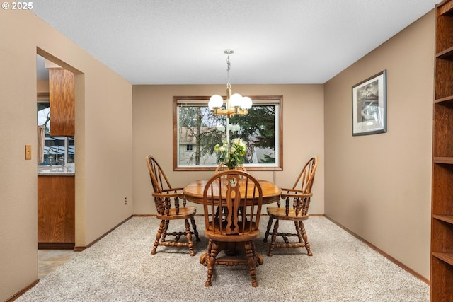 carpeted dining room featuring an inviting chandelier and baseboards