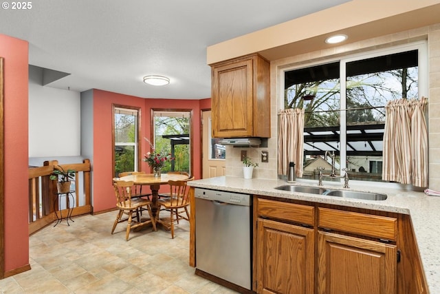 kitchen with tasteful backsplash, brown cabinets, dishwasher, and a sink