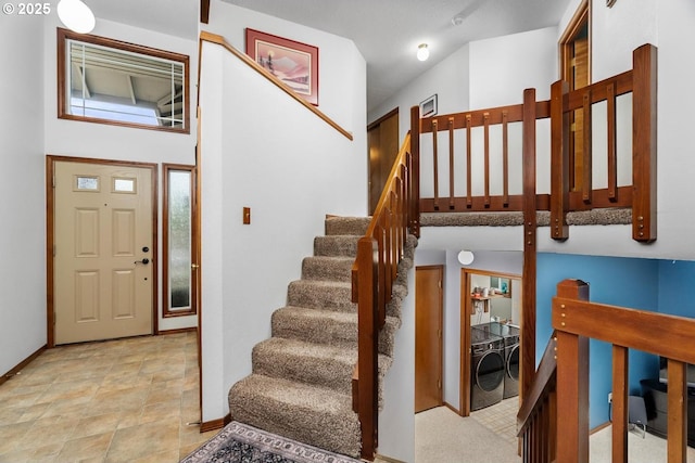 entrance foyer with washing machine and clothes dryer, stairway, stone finish flooring, and baseboards