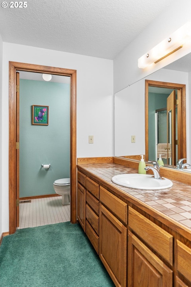 bathroom featuring a textured ceiling, carpet, vanity, and toilet