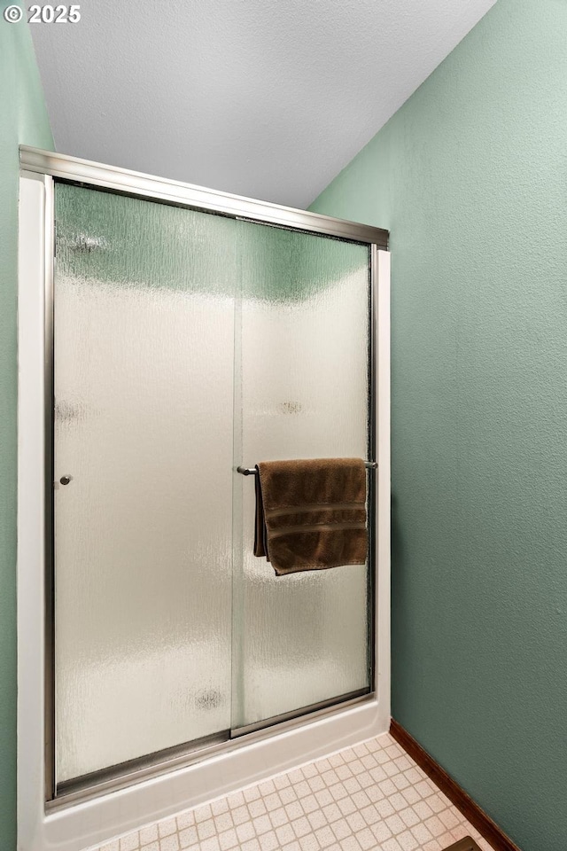 full bathroom with baseboards, a shower stall, and a textured wall