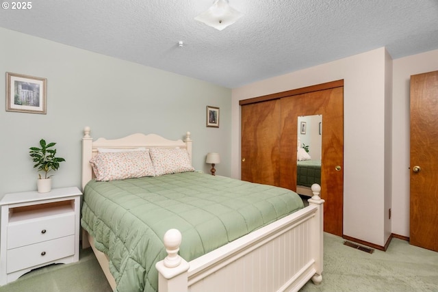 bedroom featuring carpet, visible vents, baseboards, a closet, and a textured ceiling