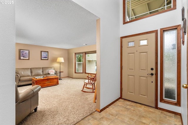 entrance foyer with light colored carpet, baseboards, a textured ceiling, and stone finish flooring