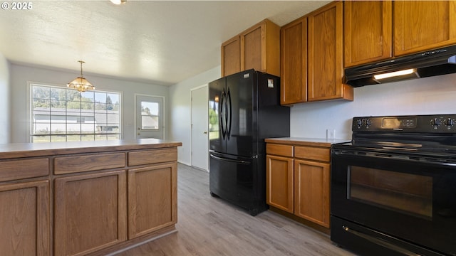 151 E Date St, Powers, OR 97466 - kitchen with black appliances, under cabinet range hood, brown cabinetry, and light wood-style flooring