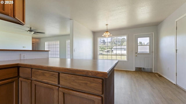 151 E Date St, Powers, OR 97466 - kitchen featuring brown cabinetry, light wood finished floors, healthy amount of natural light, and a textured ceiling