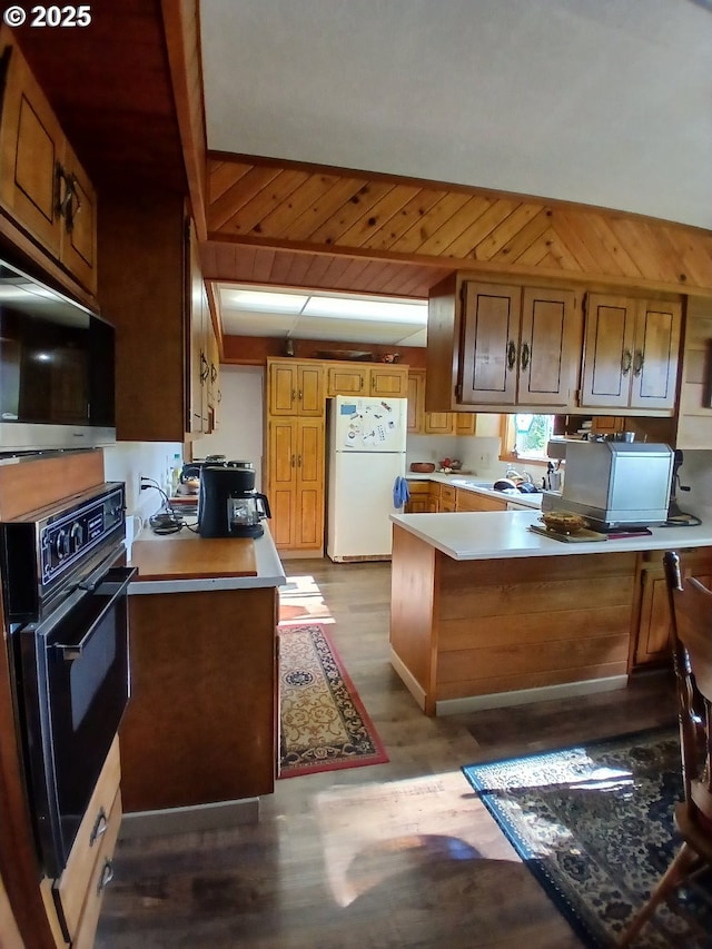 9655 8th St, Bay City, OR 97107 - kitchen featuring freestanding refrigerator, oven, stainless steel microwave, a peninsula, and light countertops