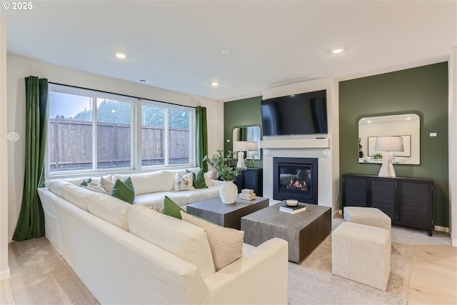 living area with a glass covered fireplace, recessed lighting, and light colored carpet