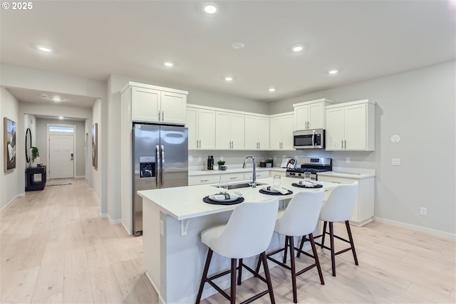 kitchen featuring a breakfast bar, light countertops, recessed lighting, appliances with stainless steel finishes, and a sink