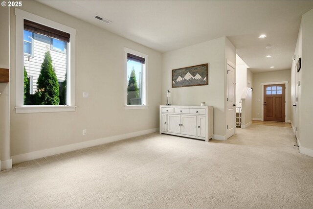 empty room featuring a healthy amount of sunlight, visible vents, and light carpet