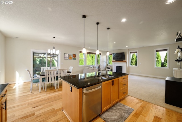 kitchen featuring a fireplace, a sink, open floor plan, dishwasher, and a center island with sink