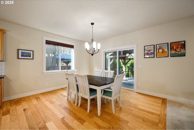 dining room with light wood-style floors, a wealth of natural light, a notable chandelier, and baseboards