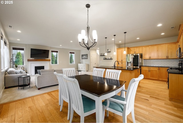 dining room with a fireplace, a notable chandelier, light wood finished floors, recessed lighting, and visible vents