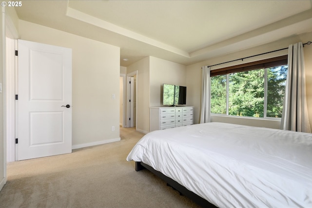 bedroom with baseboards, a tray ceiling, and light colored carpet