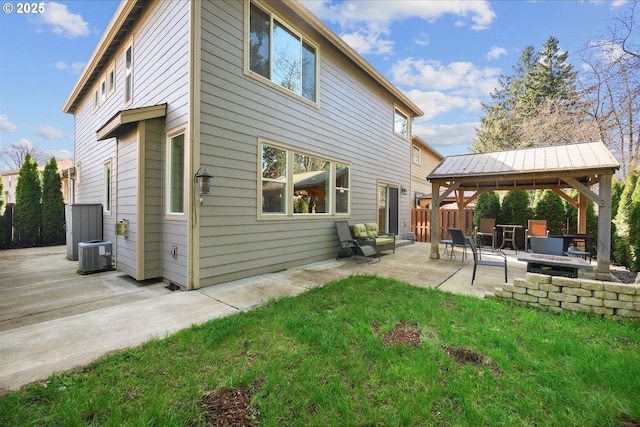 rear view of house featuring a patio, an outdoor fire pit, central AC unit, fence, and a gazebo