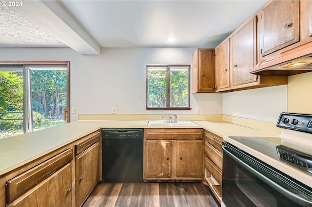 kitchen with dark wood finished floors, dishwasher, a sink, light countertops, and electric stove