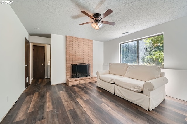 living area with dark wood-style flooring, ceiling fan, a fireplace, a textured ceiling, and visible vents