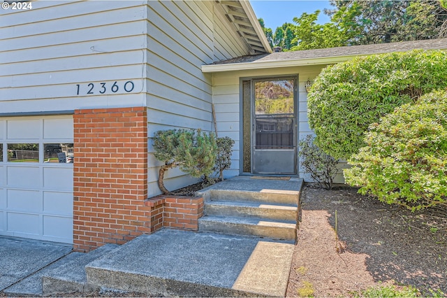 property entrance with brick siding and a garage
