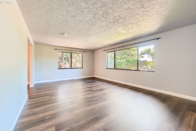 empty room featuring baseboards, dark wood-style flooring, and a textured ceiling