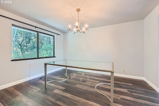 unfurnished dining area featuring baseboards, a textured ceiling, wood finished floors, and a notable chandelier