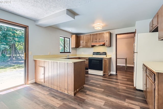 kitchen featuring range with electric stovetop, freestanding refrigerator, a peninsula, dark wood-style floors, and under cabinet range hood