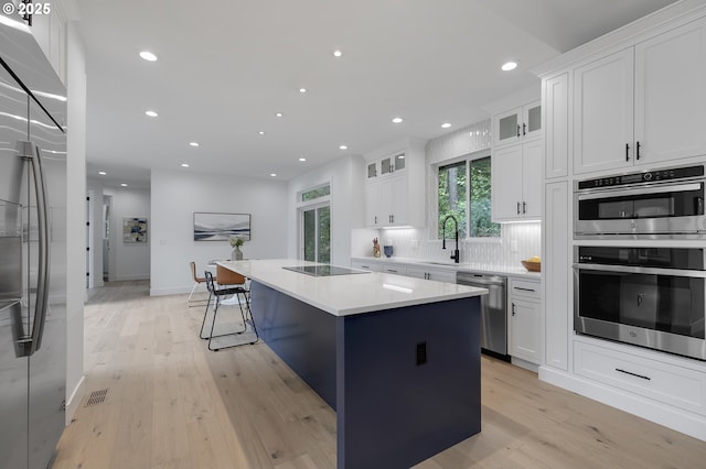 kitchen with decorative backsplash, stainless steel appliances, a kitchen island, and white cabinets