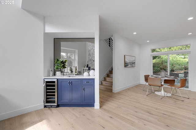 bar featuring sink, a wealth of natural light, wine cooler, and light hardwood / wood-style flooring