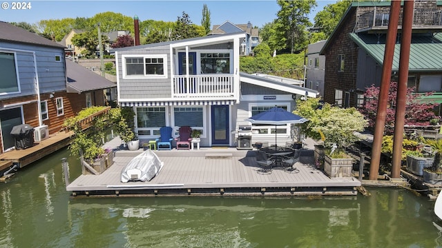 back of property with a balcony and a water view